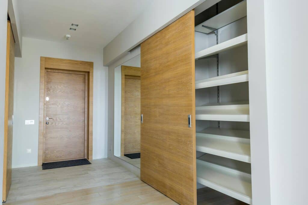 Elegant modern walk-in closet with wooden sliding door and empty shelves in a sleek minimalist style. Sliding Door Repair Gallery